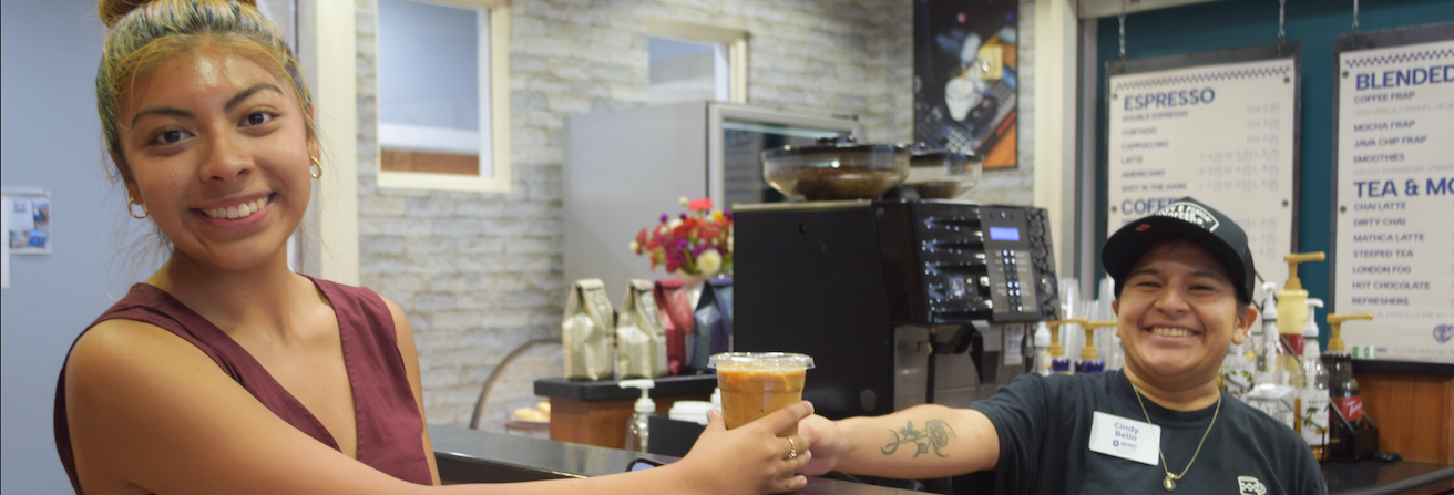 A Berry student holding a cup of coffee, with a Berry Bean'ry worker holding the same coffee.